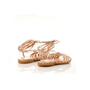 Pair of rose gold strappy sandals on a white background